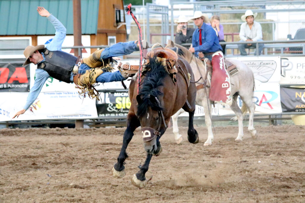 Bronc rider getting bucked off horse.