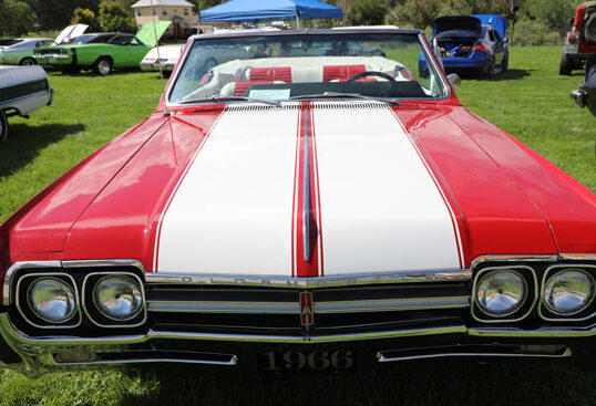 A red and white classic 1966 Oldsmobile at the fair and rodeo car show.
