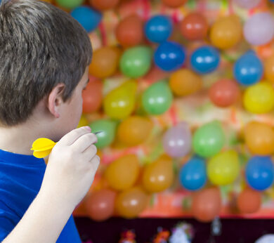 kid throwing dart at balloons